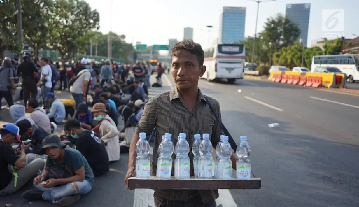Seorang pedagang minum berjualan di jalan tol dalam kota yang berada di depan Gedung DPR RI, Jakarta, Senin (30/9/2019). Adanya aksi unjuk rasa di sekitar lokasi dimanfaatkan para pedagang asongan untuk mencari rezeki. (Liputan6.com/Immanuel Antonius)