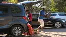 Seorang pria membawa sekantong kentang untuk pelanggan saat berjualan dari mobilnya di Harare, 23 Juni 2020. Mobil menjadi pasar bergerak di mana penduduk Zimbabwe menjual barang dagangan dari kendaraan untuk mengatasi kesulitan ekonomi yang disebabkan Covid-19. (AP Photo/Tsvangirayi Mukwazhi)