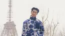 Nattawin Wattanagitiphat aktor Thailand mengenakan atasan zipper warna dasar putih dengan motif bunga navy. Dipadukan celana panjang abu-abu, sambil membawa Dior Normandie Tote bag warna hitam. [@apo555]