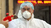 Pekerja berpakaian pelindung didesinfeksi di luar hotel yang digunakan dalam isolasi medis virus corona di Wuhan, Provinsi Hubei, China, Senin (3/2/2020). (Chinatopix via AP)