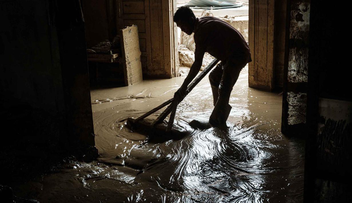 Padli, 39 tahun, membersihkan sisa material banjir berupa lumpur dari rumahnya di Aceh Tamiang, pada Minggu 14 Desember 2025. Sebagian warga yang tinggal di Aceh Tamiang, Aceh, mulai membersihkan rumah dari lumpur, sisa material banjir bandang yang menerjang wilayah mereka, akhir November 2025 lalu. (Yasuyoshi CHIBA/AFP)