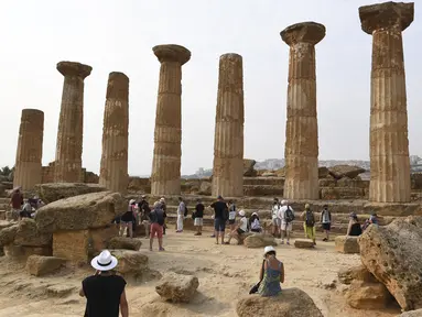 Turis saat mengunjungi Lembah Kuil selama gelombang panas di dekat Agrigento, Sisilia, Italia (11/8/2021). Gelombang panas yang berkelanjutan akan berlangsung hingga akhir pekan dengan suhu diperkirakan mencapai lebih dari 40 derajat Celcius di banyak bagian dari Italia. (AP Photo/Salvatore Cavalli)