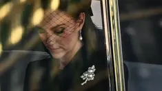 Kate Middleton berada di dalam mobil saat menghadiri prosesi persemayaman Ratu Elizabeth II di Westminster Hall di London (14/9/2022). Kate Middleton yang mendapat gelar baru sebagai Princess of Wales memakai bros berlian dan mutiara berbentuk daun. (AFP/Marco Bertorello)