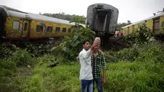 Dua remaja India berswafoto di dekat gerbon kereta yang tergelincir di Asangaon, India (29/8). Sebuah kereta penumpang mengalami kecelakaan di  sekitar 70 kilometer dari Mumbai. (AP Photo / Rafiq Maqbool)