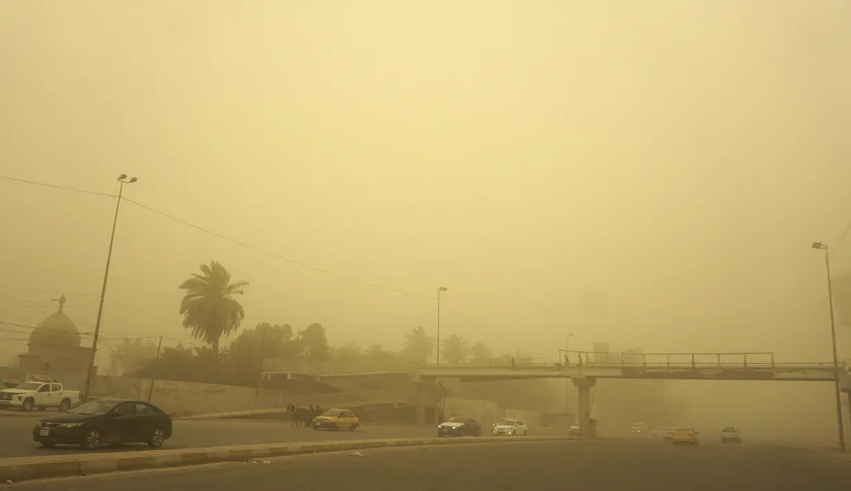 Kendaraan melaju di jalan di ibu kota Irak, saat debu tebal akibat badai pasir menyelimuti kota itu, pada Senin (23/5/2022). Irak menutup bandara dan gedung-gedung publik saat badai pasir -- yang kesembilan sejak pertengahan April -- melanda negara itu, kata pihak berwenang. (Sabah ARAR / AFP)