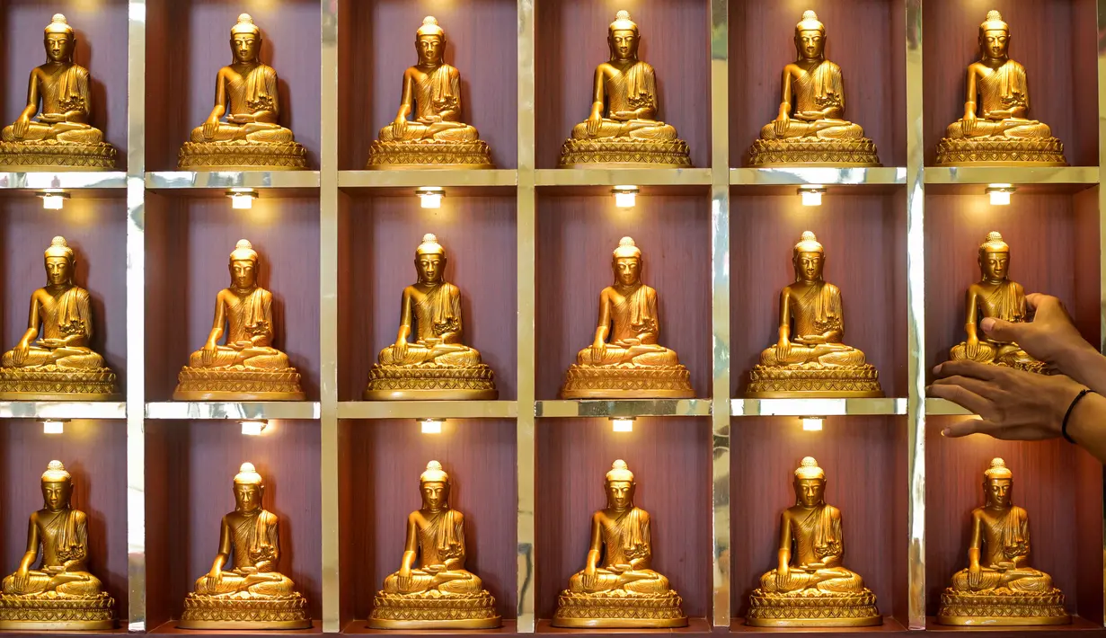 Di berbagai kota seperti Jakarta, perayaan Tahun Baru Imlek direncanakan akan berlangsung di Bundaran Hotel Indonesia dengan tema "Harmoni Imlek Nusantara". Tampak dalam foto, seorang pria menata patung Buddha sebagai persiapan perayaan Tahun Baru Imlek 2577 Kongzili di Vihara Buddhayana, Surabaya, Jawa Timur pada Senin 9 Februari 2026. (JUNI KRISWANTO/AFP)