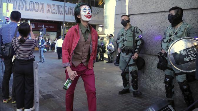 Demonstran Berkostum Halloween: Pria berkostum Halloween berjalan melewati polisi di Hong Kong, 31 Oktober 2019. Para pemrotes Hong Kong menyerukan untuk merayakan Halloween dengan mengenakan topeng yang menggambarkan pejabat pemerintah atau tokoh-tokoh menakutkan. (AP Photo/Kin Cheung)