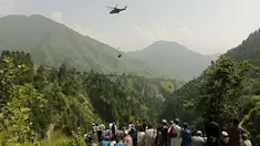 Orang-orang menyaksikan seorang tentara terjun dari helikopter selama misi penyelamatan untuk menyelamatkan para siswa yang terjebak di keeta gantung di desa Pashto di provinsi pegunungan Khyber Pakhtunkhwa, pada 22 Agustus 2023. (AFP)