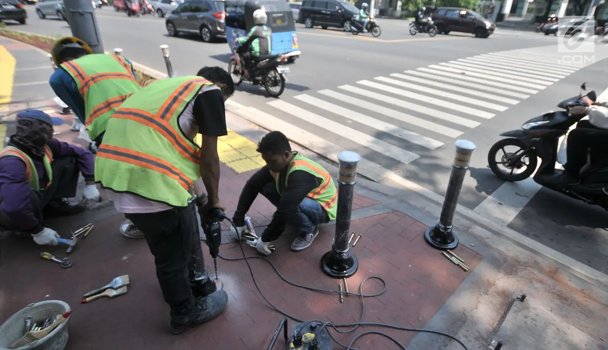 Pekerja memasang Bolar atau tiang pembatas pedestrian di kawasan Tugu Tani, Jakarta, Minggu (9/9). Pemasangan Bolar bertujuan menjaga keindahan jalur pedestrian dan mencegah penyalahgunaan fungsi.(merdeka.com/ Iqbal S. Nugroho)