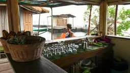 Seorang wanita menunggu di sebuah restoran di pulau buatan dari sampah plastik daur ulang di Abidjan, Pantai Gading pada Agustus 2019. Eric Becker asal Prancis membangun sebuah pulau terapung dari sekitar 700.000 sampah plastik daur ulang yang dikumpulkan di daerah sekitarnya. (ISSOUF SANOGO/AFP)