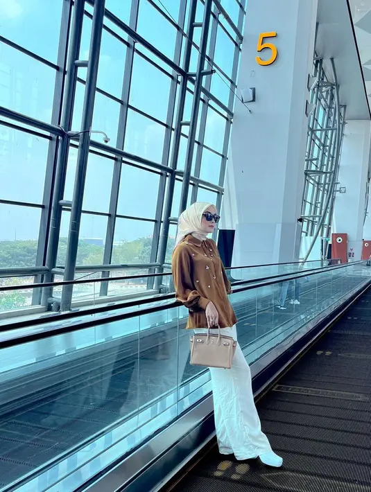 Airport look kece ala Citra Kirana. Citra Kirana padukan kemeja cokelat dengan celana dan sepatu putih. Hijab kuning, sunglasses, dan tas Hermesnya yang bernuansa netral menyempurnakan keseluruhan penampilan Citra Kirana di sini. [Foto: Instagram/citraciki]