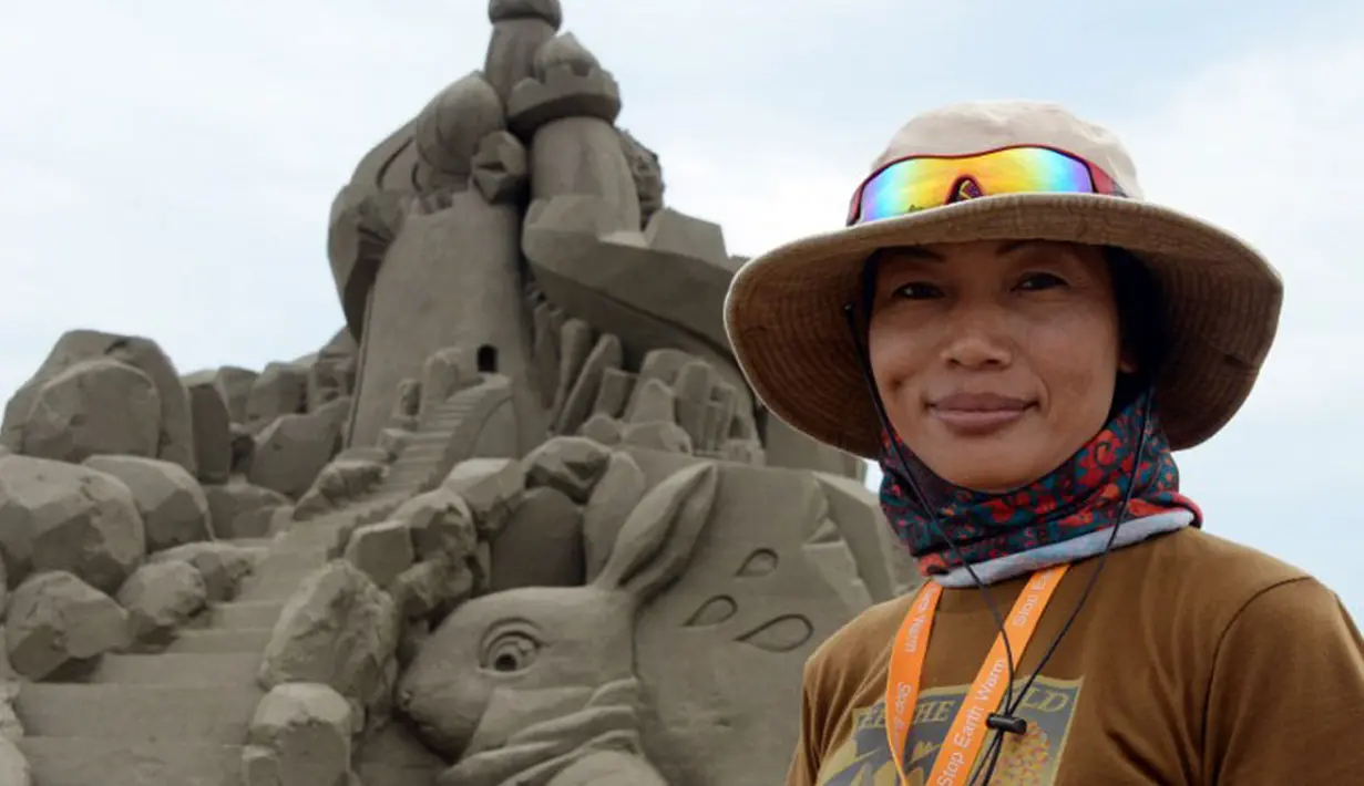 Seniman patung pasir Jepang, Yoshiko Matsugi, berpose di depan karyanya yang akan dipamerkan dalam pameran bertema Asahi Sand Sculpture di pantai Yasashigaura, Asahi, Chiba, (13/7/2014). (AFP PHOTO/Toshifumi Kitamura)