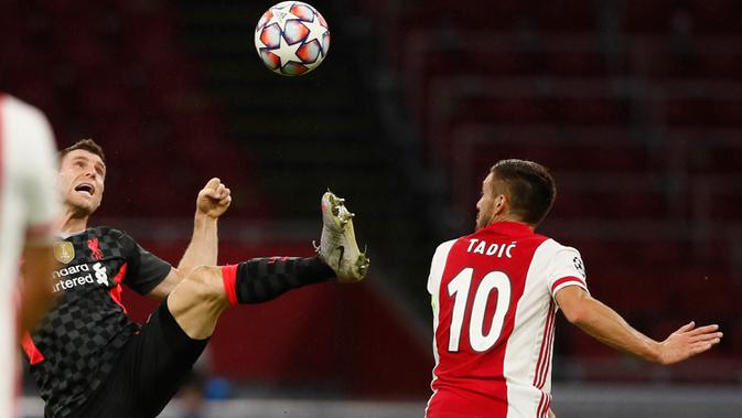 Gelandang Liverpool, James Milner berebut bola dengan pemain Ajax Amsterdam,  Dusan Tadic pada pertandingan pertama Grup D Liga Champions 2020 di Johan Cruijff Arena, Kamis (22/10/2020) dini hari WIB. Liverpool susah payah menang tipis 1-0 di kandang Ajax. (AP Photo/Peter Dejong)