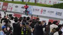 Untuk pertama kalinya, robot humanoid berkompetisi secara resmi berdampingan dengan ribuan pelari manusia dalam lintasan sejauh 21,0975 km. Tampak dalam foto, para jurnalis merekam saat sebuah robot berkompetisi dalam Beijing E-Town Half Marathon dan Humanoid Robot Half-Marathon yang diadakan di pinggiran Beijing, Minggu 19 April 2026. (AP Photo/Andy Wong)