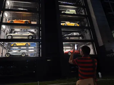 Seorang pria mengambil gambar vending machine atau mesin penjual otomatis berisi mobil-mobil mewah di gedung Autobahn Motors, Singapura, Kamis (18/5). Vending machine berbentuk bangunan bertingkat itu dapat menampung hingga 60 mobil. (ROSLAN RAHMAN/AFP)