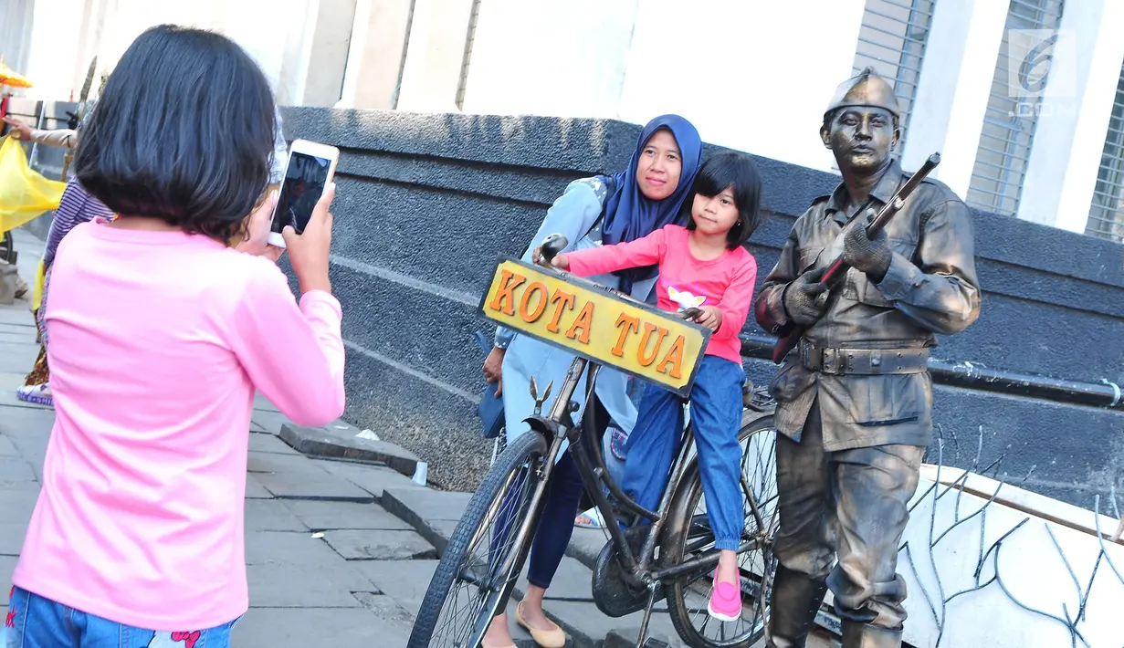 Pengunjung berfoto bersama "manusia patung" di kawasan Kota Tua, Jakarta, Kamis (21/9). Kawasan Kota Tua menjadi salah satu tujuan warga Jakarta dan sekitarnya untuk mengisi libur Tahun Baru Islam. (Liputan6.com/Helmi Afandi)