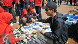 Buruh membeli tongsis saat demo memperingati hari lahirnya organisasi buruh internasional World Federation of Trade Unions (WFTU) di Jakarta (3/10/2015).  Sejumlah PKL memanfaatkan demo buruh untuk meraup sedikit keuntungan. (Liputan6.com/Gempur M Surya)