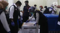 Kepala Dinkes Kabupaten Bekasi, dr Sri Enny Mainarti membuka kotak berisi vaksin Covid-19 Sinovac setibanya di Gudang UPTD Farmasi Kabupaten Bekasi,  Tambun, Rabu (27/1/2021). Sebanyak 12.000 dosis vaksin COVID-19 dari Biofarma Bandung tiba di Kabupaten Bekasi. (Liputan6.com/Herman Zakharia)