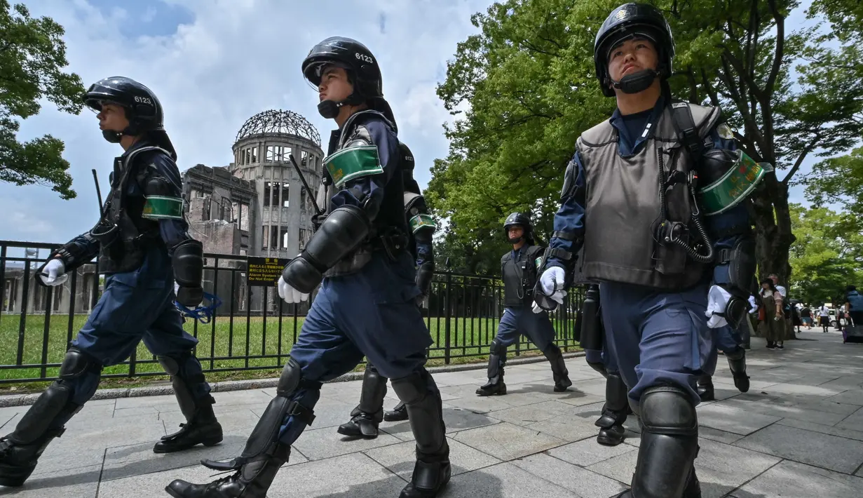 Polisi dengan perlengkapan anti huru hara berbaris melewati Kubah Bom Atom (belakang kiri) saat mereka mengamankan area tersebut di kota Hiroshima, Prefektur Hiroshima pada 5 Agustus 2025. (Richard A. Brooks/AFP)