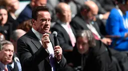 Mantan Gubernur California, Arnold Schwarzenegger berbicara pada forum KTT One Planet Summit di Paris, Selasa (12/12). Aktor AS itu mencuri perhatian dengan dua cincin di jari yang salah satunya bermotif tengkorak warna perak. (AFP PHOTO/Eric FEFERBERG)