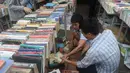 Seorang pria mencari buku selama pameran buku bekas di Hanoi, Vietnam  (26/10).( AFP Photo/Hoang Dinh Nam)