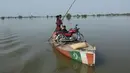 Sebuah perahu membawa orang dan sepeda motor untuk berkeliling daerah banjir di kota Burewala, di distrik Vehari di provinsi Punjab, pada 25 Agustus 2023. (AFP/Shahid Saeed Mirza)