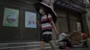 Seorang pria bermasker dan memegang payung saat berjalan melewati seorang pria tua yang mengumpulkan barang-barang daur ulang di depan toko-toko kosong di Qianmen Street di Beijing, Rabu, 17 Agustus 2022. Pabrik-pabrik di barat daya China telah ditutup dan sebuah kota memberlakukan pemadaman bergilir setelah waduk yang digunakan untuk menghasilkan tenaga air mulai menipis akibat kekeringan yang memburuk. (AP Photo/Andy Wong)