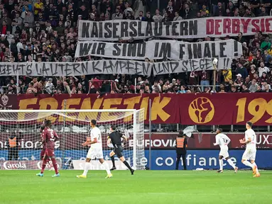 Suporter FC Metz membentangkan spanduk bertulisakan "Pemenang derby Kaiserlautern, kami berada di final" untuk mendukung FC Kaiserlautern yang mencapai final Piala DFB Pokal pada laga lanjutan Liga Prancis 2023/2024 melawan RC Lens di Saint-Symphorien Stadium, Longeville-les-Metz, Prancis, Sabtu (13/04/2024) dini hari WIB. (AFP/Jean-Christophe Verhaegen)