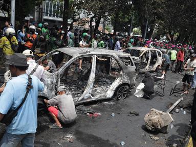 Warga melihat sisa mobil yang dibakar massa ketika aksi unjuk rasa menuntut pengusutan kasus penabrakan pengemudi ojek online di sekitar Markas Komando Korps Brigade Mobil (Brimob) Polda Metro Jaya, kawasan Kwitang, Pasar Senen, Jakarta, Jumat (29/8/2025). (merdeka.com/Arie Basuki)
