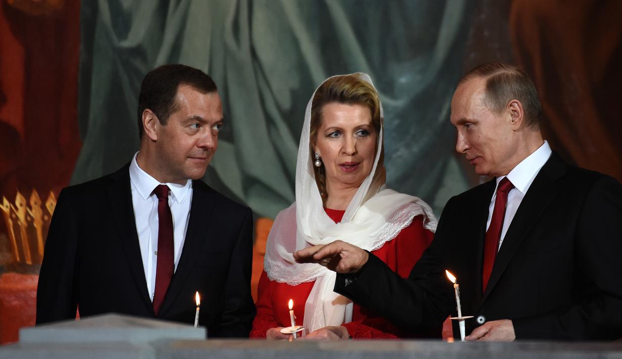 Presiden Rusia Vladimir Putin (kanan) bersama Perdana Menteri Rusia Dmitry Medvedev (kiri) dan istrinya Svetlana saat menjalani prosesi Paskah Ortodoks di Gereja Katedral Kristus Juru Selamat di Moskow, Rusia,(16/4). (AFP Photo / Vasily Maximov)