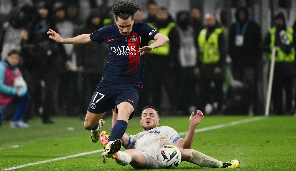 Pemain Paris Saint-Germain, Vitinha, berusaha melewati pemain Marseille, Jordan Veretout, dalam duel pekan ke-27 Ligue 1 2023/2024 di Stade Velodrome, Senin (1/4/2024). (AFP/Christophe Simon)
