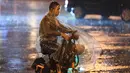 Seorang pria mengendarai sepeda di bawah hujan di Distrik Chaoyang, Beijing, China (12/8/2020). Badan meteorologi Beijing mengeluarkan peringatan siaga kuning untuk hujan badai. (Xinhua/Ju Huanzong)
