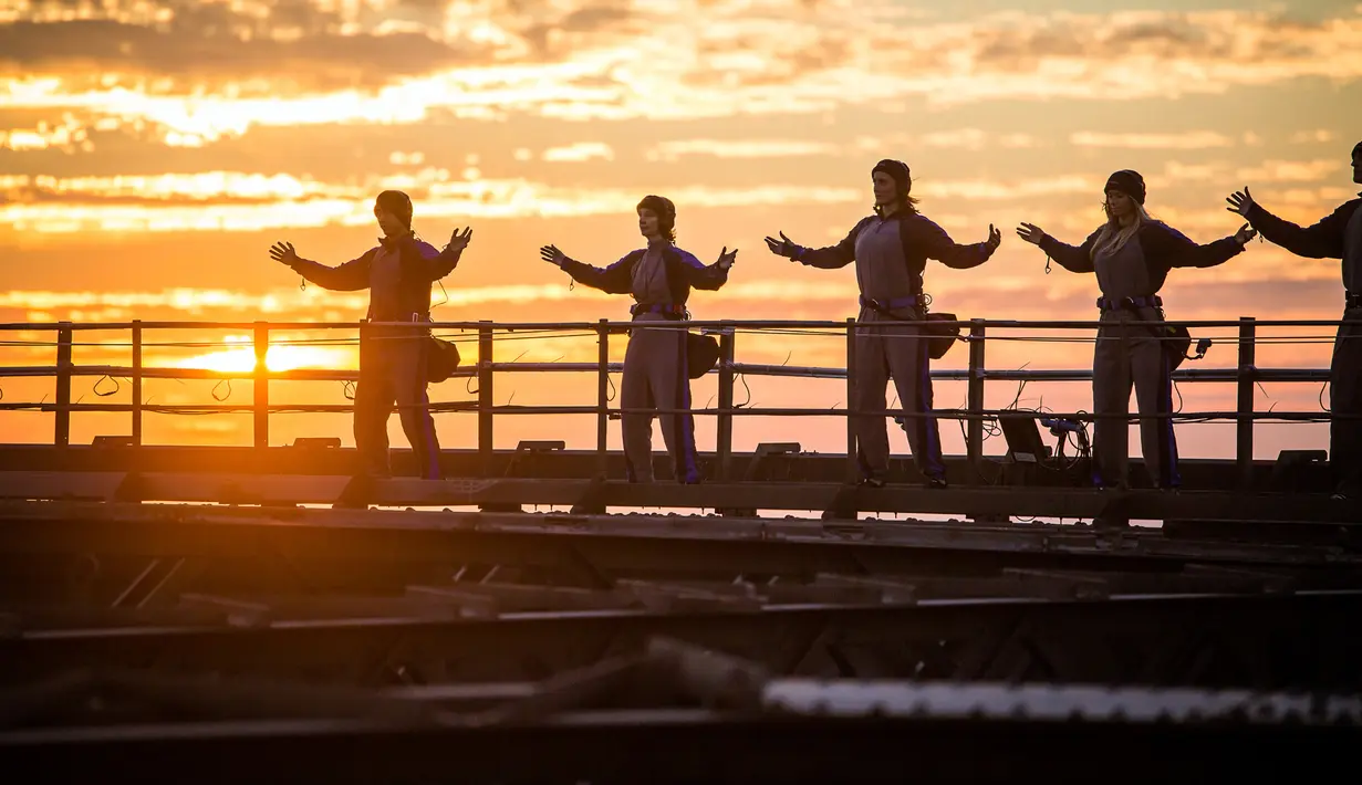 Praktisi Tai Chi melakukan latihan dengan latar belakang matahari terbenam di atas Jembatan Sydney Harbour, Australia, Selasa (2/5). Acara ini diselenggarakan oleh Akademi Tai Chi dan Qigong Australia. (Handout / BRIDGECLIMB SYDNEY / AFP)