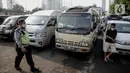 Polisi berjalan melewati kendaraan travel gelap yang disita jajaran Direktorat Lalu Lintas Polda Metro Jaya, Jakarta, Kamis (29/4/2021). Sebanyak 115 kendaraan travel gelap diamankan karena diduga kuat mengangkut pemudik di tengah masa pengetatan larangan mudik 2021. (Liputan6.com/Faizal Fanani)