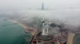 Foto udara ini memperlihatkan Kuwait Towers ketika pagi berkabut di Kota Kuwait terlihat dalam foto udara, Selasa (14/3/2023). Kemunculan kabut memperlihatkan pemandangan indah, dimana kota Kuwait terlihat seperti negeri di atas awan. (Photo by Yasser Al-Zayyat / AFP)