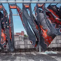 Seorang pekerja mengeringkan kain batik di Sidoarjo, Jawa Timur, Sabtu (1/10/2022). Indonesia akan memperingati Hari Batik Nasional pada 2 Oktober. (JUNI KRISWANTO/AFP)
