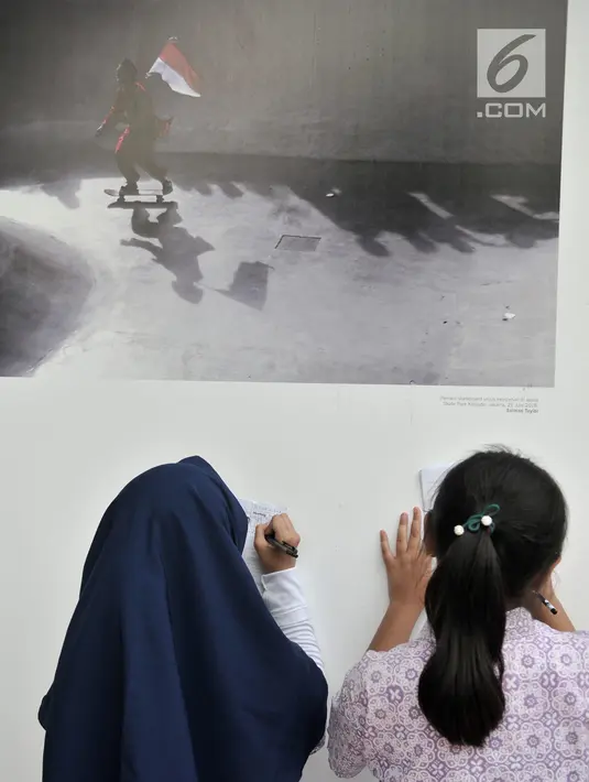 Siswa SD Negeri Menteng 01 menulis keterangan pada salah satu karya foto dalam pameran fotografi Rekam Jakarta di Taman Menteng, Kamis (29/8/2019). Kegiatan tersebut dalam rangka edukasi bagi siswa mengenal profesi foto jurnalistik. (merdeka.com/Iqbal S Nugroho)