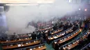 Para politisi meninggalkan ruangan yang dipenuhi asap gas air mata dalam rapat parlemen di ibu kota Kosovo, Pristina, Rabu (21/3). Aksi pelemparan kaleng gas air mata tersebut dilakukan oleh seorang anggota Partai Vatevendosje. (AP Photo/Visar Kryeziu)