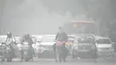 Seorang pengendara sepeda dengan wajah ditutupi masker melintasi sebuah jalan di pagi hari yang dingin dan berkabut di New Delhi pada tanggal 18 November 2024. (Money SHARMA/AFP)