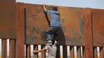 Seorang pemuda dibantu temannya memanjat tembok besi perbatasan antara Meksiko dan Amerika Serikat di negara bagian Chihuahua, Meksiko (6/4). Mereka menyeberang secara ilegal ke Sunland Park dari Ciudad Juarez. (AFP/Herika Matinez)
