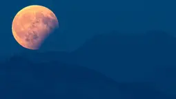 Gerhana bulan parsial terlihat di atas Pegunungan Alpen Bernese, Swiss, Senin (7/8). Gerhana bulan parsial bisa dilihat di seluruh Indonesia, sebagian benua Eropa, sebagian Afrika, Australia dan seluruh negara di benua Asia. (Anthony Anex/Keystone via AP)