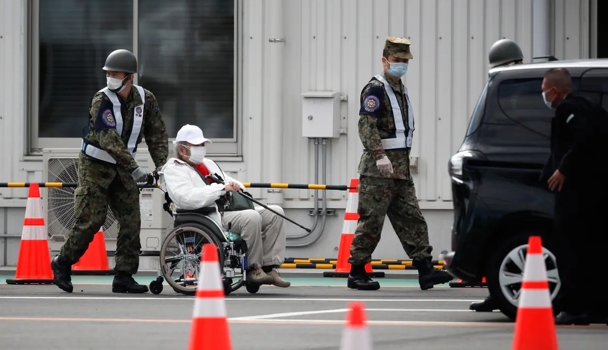 Petugas mengawal penumpang kapal pesiar Diamond Princess yang dikarantina di sebuah pelabuhan di Yokohama, Jepang, Rabu (19/2/2020). Satu WNI di kapal pesiar Diamond Princess kembali dinyatakan positif terinfeksi virus corona (COVID-19). (AP Photo/Jae C. Hong)