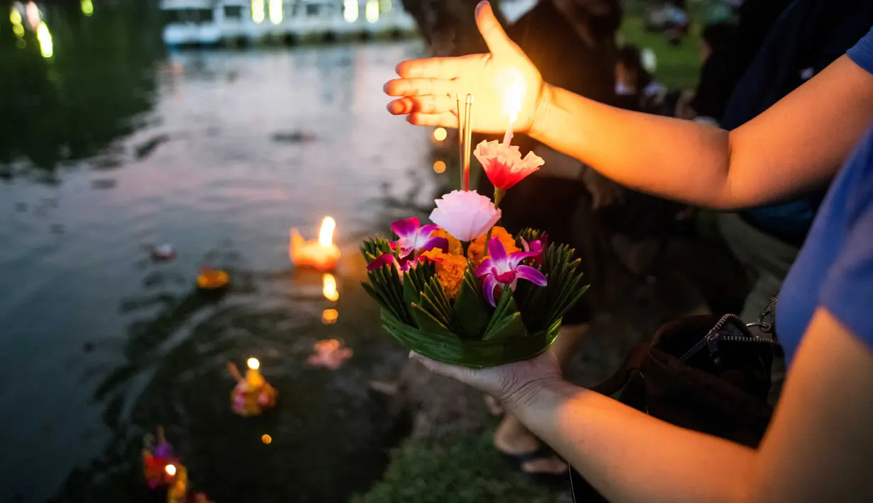 Seorang wanita bersiap menghayutkan 'krathong' untuk merayakan festival Loy Krathong di sebuah danau di Bangkok, Kamis (22/11). Loy Krathong adalah ritual melarung wadah berbentuk lotus yang didalamnya diberi sesajen, lilin dan dupa (Jewel SAMAD/AFP)
