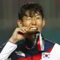 Penyerang Korea Selatan, Son Heung-min, menggigit mendali, usai menjuarai Asian Games dengan mengalahkan Jepang di Stadion Pakansari, Jawa Barat, Sabtu (1/9/2018). (AP/Bernat Armangue)