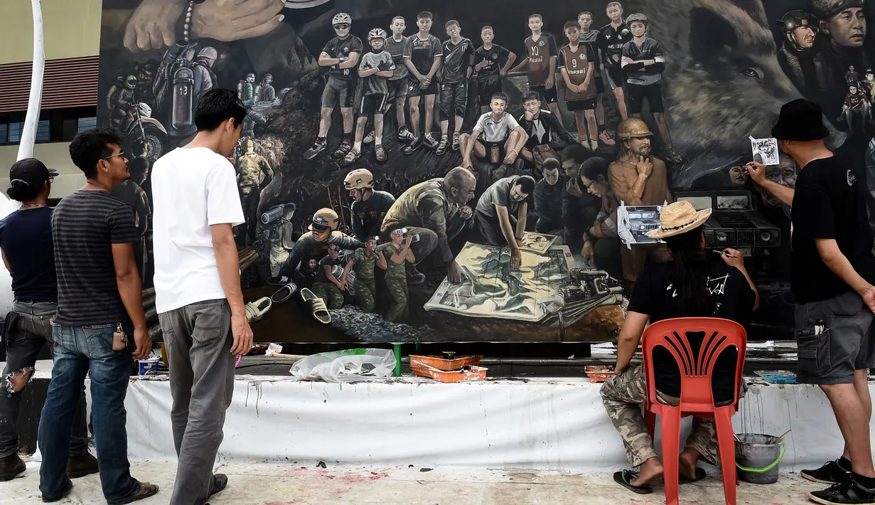 Seniman lokal menyelesaikan mural berjudul 'The Heroes' di Chiang Rai, 18 Juli 2018. Mural itu untuk menghormati upaya penyelamatan 12 remaja dan pelatih sepak bola mereka yang terperangkap di  gua selama lebih dari dua minggu. (AFP/Lillian SUWANRUMPHA)
