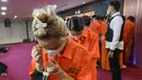 Petugas Imigrasi Indonesia mengawal tahanan di Kantor Imigrasi Jakarta pada Selasa 18 November 2025. Kantor Imigrasi Jakarta menggelar konferensi pers terkait penangkapan puluhan warga negara asing asal China. (BAY ISMOYO/AFP)