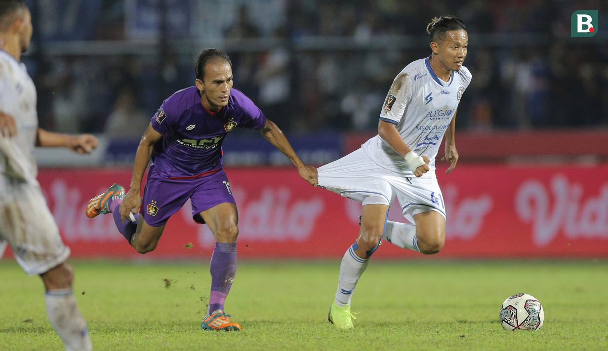 Pemain Persik Kediri, Faris Aditama (kiri) berusaha menghentikan pergerakan pemain Arema FC, Dendi Santoso dalam lanjutan pertandingan babak penyisihan Grup D Piala Presiden 2022 antara Persik Kediri menghadapi Arema FC di Stadion Kanjuruhan, Malang, Jawa Timur, Rabu (15/6/2022). (Bola.com/Arief Bagus)
