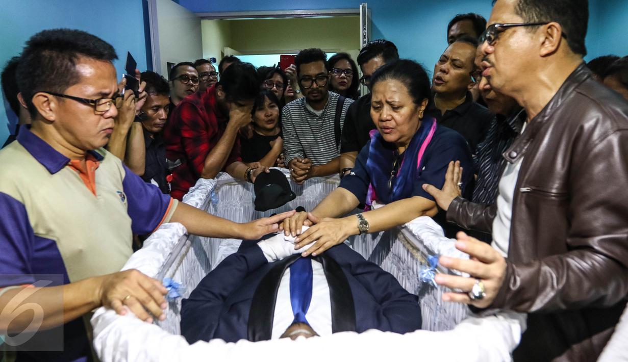 Kerabat dan keluarga berdoa di depan jenazah Mike Mohede di dalam peti di RS Bintaro Premiere, Tangsel, Minggu (31/7). Mike Mohede mengembuskan napas terakhirnya saat tidur siang di kamar seusai bermain game. (Liputan6.com/Fery Pradolo)