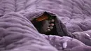 Seorang pria tunawisma yang terbungkus selimut tidur di sepanjang pinggir jalan pada suatu pagi musim dingin di New Delhi, India, Selasa (2/1/2024). (Money SHARMA / AFP)