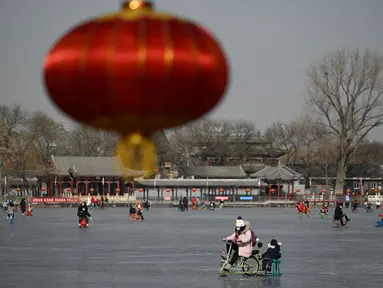 Orang-orang menggunakan kereta luncur di danau beku di Beijing pada Selasa (12/1/2021). Ketika musim dingin tiba, danau di Beijing banyak yang membeku dan dijadikan area ice skating musiman. (Photo by WANG Zhao / AFP)